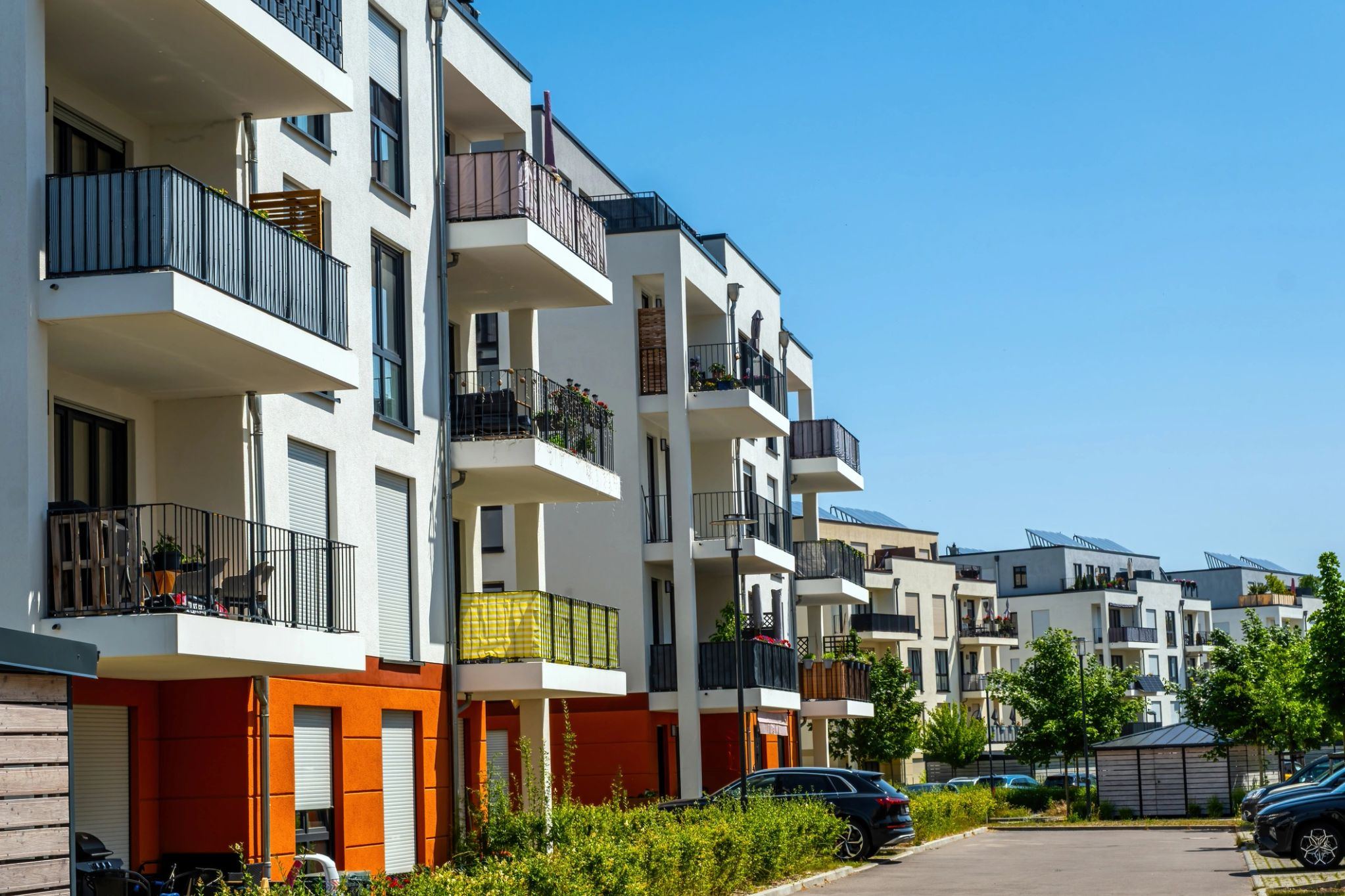 Modern low-rise apartment buildings with balconies along a residential street
