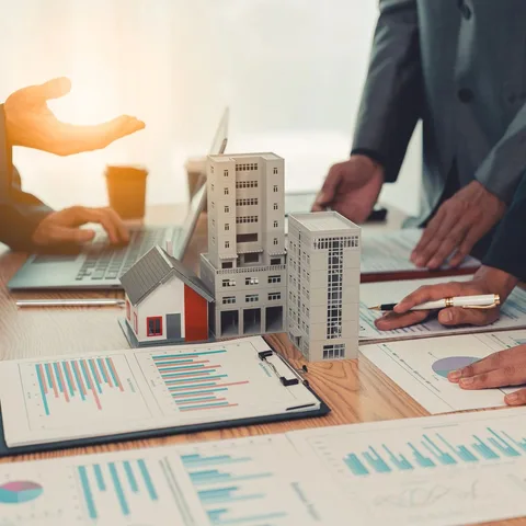 Architectural models of a house and apartment buildings resting on financial charts